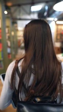 Muhteşem bir kız kitapçıdaki kitaplıkların arasında dolaşırken görüldü. Yüksek kalite 4k görüntü