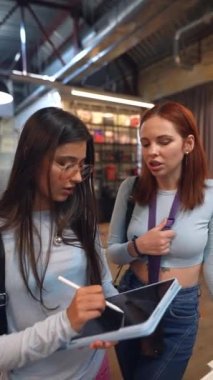 Kitapçıda iki çekici genç kadın konuşurken görülüyor. Yüksek kalite 4k görüntü