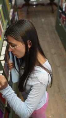 Kitaplığın yanında, tabletli hoş bir genç bayan görülüyor. Yüksek kalite 4k görüntü