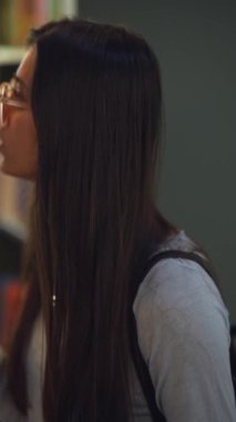 Muhteşem bir kız kitapçıdaki kitaplıkların arasında dolaşırken görüldü. Yüksek kalite 4k görüntü