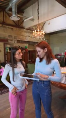 Kütüphanede her yerde kitaplıkları olan iki genç kadın var. Yüksek kalite 4k görüntü