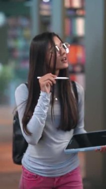 Kitapçıların ortasındaki davetkar atmosferde genç ve enerjik bir bayan kitapların arasında geziniyor. Yüksek kalite 4k görüntü