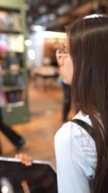 Kitapçı ortamında, hoş genç bir bayan sakin bir yürüyüşün tadını çıkarıyor. Yüksek kalite 4k görüntü