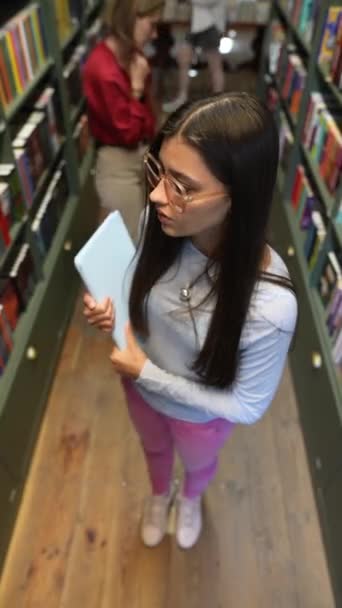 在图书馆的书架上 一个惊艳的年轻女子拿着一块石碑 高质量的4K镜头 — 图库视频影像