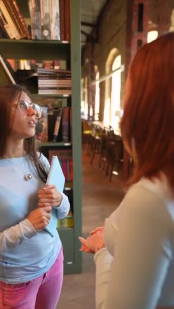 Twee Prachtige Jonge Vrouwen Worden Gezien Bibliotheek Elk Met Een — Stockvideo