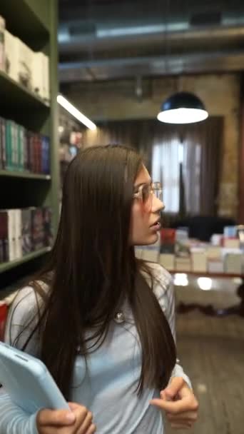 Piękna Dziewczyna Tabletem Ręku Jest Przy Regałach Bibliotece Wysokiej Jakości — Wideo stockowe