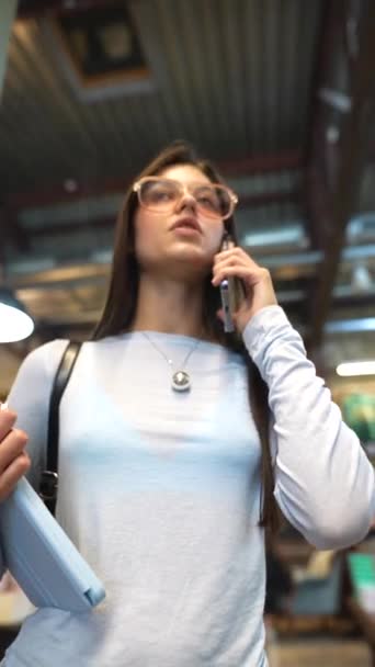 Una Chica Joven Vibrante Hablando Por Teléfono Entre Las Librerías — Vídeo de stock