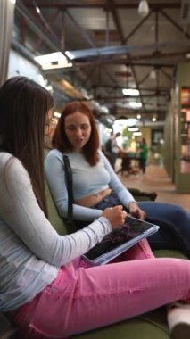 Kitapçıda, iki genç ve çarpıcı arkadaş sohbet ediyorlar. Yüksek kalite 4k görüntü