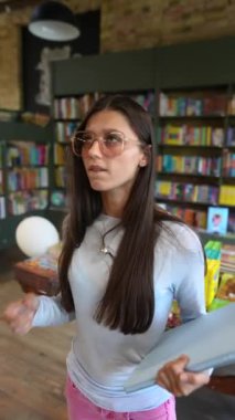 Her ikisi de güzel olan iki genç kadın, elinde tablet olan bir kitapçı hakkında sohbet ediyorlar. Yüksek kalite 4k görüntü