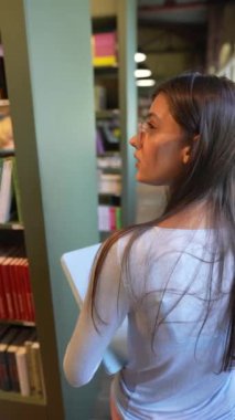 Elinde tableti olan güzel bir kız kitapçıyla ilgili görüşlerini paylaşıyor. Yüksek kalite 4k görüntü