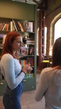 Kütüphanede iki genç bayan var, etrafı kitaplıklarla çevrili. Yüksek kalite 4k görüntü