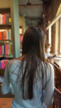 Kitaplığın yanında, tabletli hoş bir genç bayan görülüyor. Yüksek kalite 4k görüntü