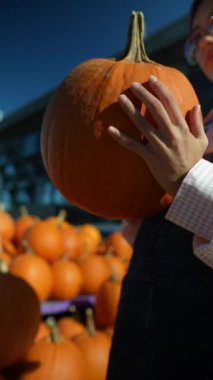 Hareketli pazarda, bir bayan satıcı satılık önemli bir portakal kabağı sergiliyor. Yüksek kalite 4k görüntü