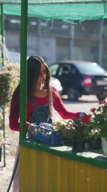 Tedarikçi olarak çalışan bir kız, markette envanterindeki bitkilerle hevesle ilgilenirken görülüyor. Yüksek kalite 4k görüntü