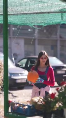 Pazar sahnesinin ortasında, güzel bir kadın satıcı kurbanlarının bir parçası olan bitkilerle sevgiyle ilgileniyor. Yüksek kalite 4k görüntü