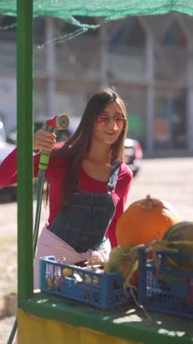 Çekici bir satıcı, pazarda satılmak üzere bitki ve balkabaklarını hevesle sularken görülüyor. Yüksek kalite 4k görüntü