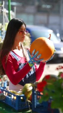 Satıcı olarak çalışan muhteşem bir kadın, pazarda sattığı balkabaklarını sunarken görülüyor. Yüksek kalite 4k görüntü