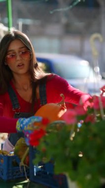 Pazar sahnesinin ortasında, güzel bir kadın satıcı kurbanlarının bir parçası olan bitkilerle sevgiyle ilgileniyor. Yüksek kalite 4k görüntü