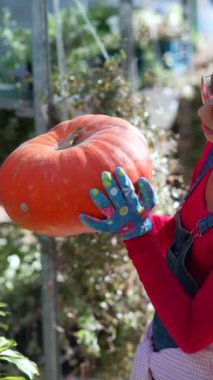 Hareketli bir pazarda, dişi bir çiftçi büyük portakal kabağını tutkuyla satışa sunuyor. Yüksek kalite 4k görüntü