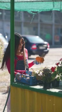 Hareketli bir pazarda, bir bayan satıcı bitkileri tutkuyla besliyor. Yüksek kalite 4k görüntü