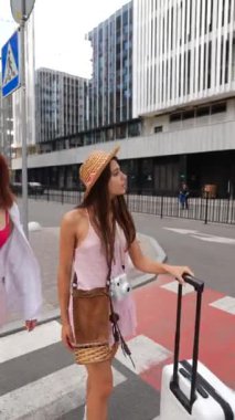 Cesur genç bayanlardan oluşan bir ikili, bir bavul ve eşyayla birlikte şehir sokaklarında yürüyor. Yüksek kalite 4k görüntü