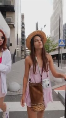 İki dinamik genç kadın ellerinde bavulları ve eşyaları ile şehrin sokaklarında geziniyor. Yüksek kalite 4k görüntü