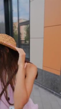 Şapka takan ve elinde kamera olan genç ve güzel bir kadın şehir caddelerinde dolanıyor. Yüksek kalite 4k görüntü