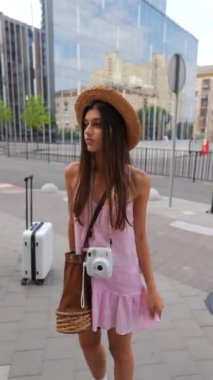 Güzel, şapkalı genç bir kadın elinde bir kamerayla tesadüfen şehirde geziniyor. Yüksek kalite 4k görüntü