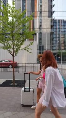 Parlak genç kızlar ellerinde bir bavul ve eşyayla şehrin sokaklarında dolaşıyorlar. Yüksek kalite 4k görüntü