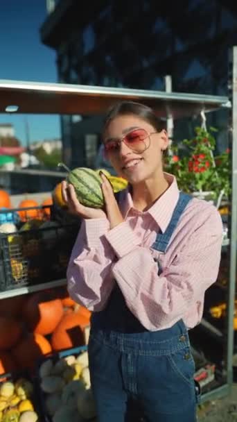一位年轻的女农场主正在展示一个他们在市场上出售的绿色条纹南瓜 高质量的4K镜头 — 图库视频影像