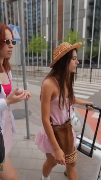 スーツケースと所持品を伴う 活気に満ちた若い女性のデュオが都市の通りをトレッキングしています 高品質の4K映像 — ストック動画