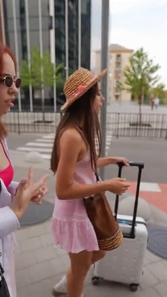 2人の熱狂的な若い女の子が街の通りをゆっくり歩き スーツケースとアイテムを運んでいます 高品質の4K映像 — ストック動画