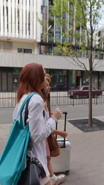 两个充满热情的年轻姑娘 提着手提箱和她们的东西 悠闲地走在城市的街道上 高质量的4K镜头 — 图库视频影像