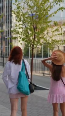 Şehir manzarasının ortasında, valizli ve çantalı iki enerjik genç kadın caddelerde ilerliyorlar. Yüksek kalite 4k görüntü