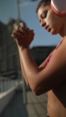 Formda, spor giyinmiş genç bir bayan yaz boyunca şehrin güneşli sokaklarında spor yapıyor. Yüksek kalite 4k görüntü