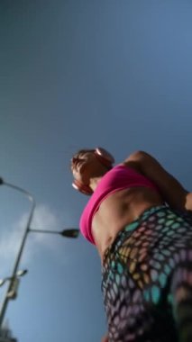 Açık havada spor kıyafetleriyle egzersiz yapan genç ve güzel bir kadının düşük açılı çekimi. Yüksek kalite 4k görüntü