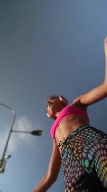 Parlak spor kıyafetleri içindeki çarpıcı genç bir bayan sokakta çalışırken alçak bir açıdan yakalandı. Yüksek kalite 4k görüntü