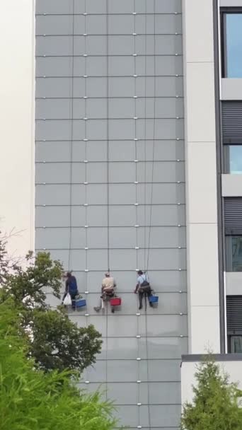 三名身穿工作服的男子正在一个高层建筑物上进行窗户清洁活动 高质量的4K镜头 — 图库视频影像