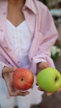 Çiftçi pazarında satıcı olarak çalışan zarif genç bir bayan, farklı elma türlerini güzel bir şekilde anlatıyor. Yüksek kalite 4k görüntü