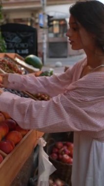 Canlı genç bir kadın satıcı çiftçi pazarında satılacak meyveleri düzenlemekten sorumludur. Yüksek kalite 4k görüntü