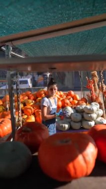Hareketli bir pazarda, dişi bir çiftçi büyük portakal kabağını tutkuyla satışa sunuyor. Yüksek kalite 4k görüntü