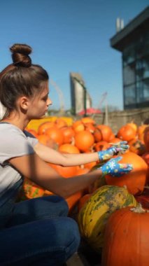 Pazar yerinde, zarif genç bir bayan satıcı satılık balkabaklarını tanıtıyor. Yüksek kalite 4k görüntü