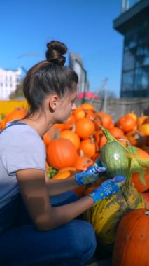 Hareketli bir pazarda, bir bayan satıcı tutkuyla satılık balkabaklarını gösteriyor. Yüksek kalite 4k görüntü