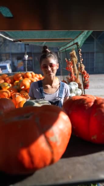 一位聪明的年轻女农场主正在展示她在市场上卖的南瓜 高质量的4K镜头 — 图库视频影像