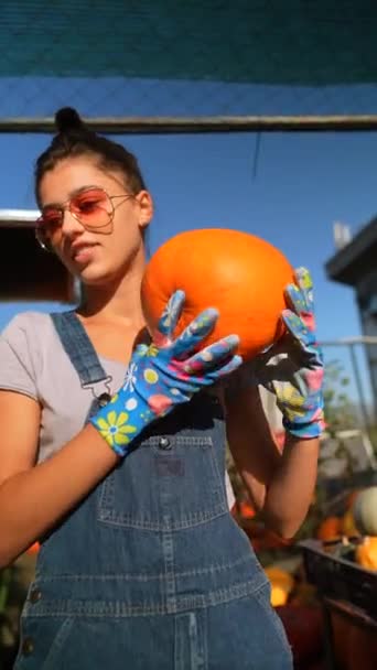 賑やかな市場では 女性農家が販売のための大きなオレンジ色のカボチャを情熱的に披露しています 高品質の4K映像 — ストック動画