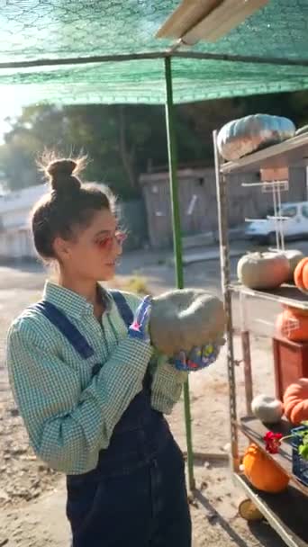 在市场摊位上 一位年轻的女摊贩正在卖力地展示南瓜 作为她选择的一部分 高质量的4K镜头 — 图库视频影像