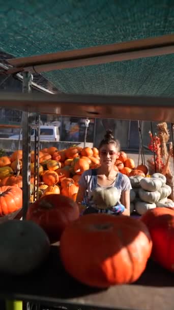 女性農家は 市場で販売される大きなオレンジ色のカボチャを熱狂的に展示しています 高品質の4K映像 — ストック動画