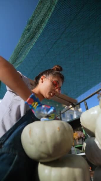 市場のシーンの中で 活発な若い女性農夫が彼女の提供の一部であるカボチャを展示しています 高品質の4K映像 — ストック動画