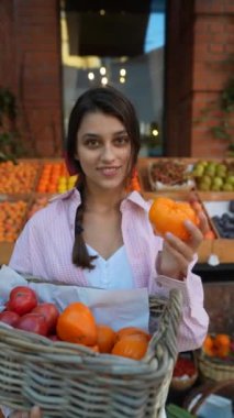 Avrupalı çiftçi pazarındaki zarif genç bir kadın sebzeleri zarifçe sepete koyuyor. Yüksek kalite 4k görüntü