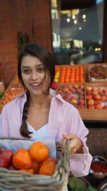 Avrupalı genç bir kadın çiftçi pazarında sebzeleri sepete koyarak çevreci dostluğa olan bağlılığını sergiliyor. Yüksek kalite 4k görüntü